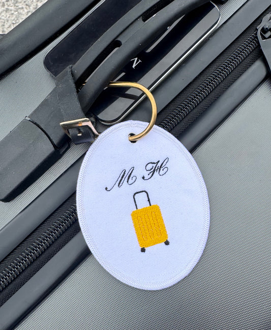 A key ring with the initials “MH” and a suitcase icon